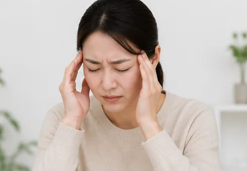 양손으로 관자놀이를 누르며 얼굴을 찡그린 여성